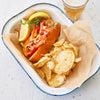 Lobster roll, lemons, and chips in a platter